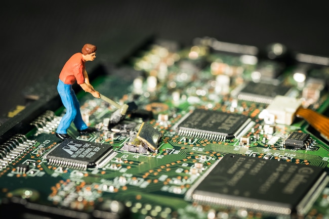 La figurine d'un ouvrier casse les circuits intégrés d'une carte informatique